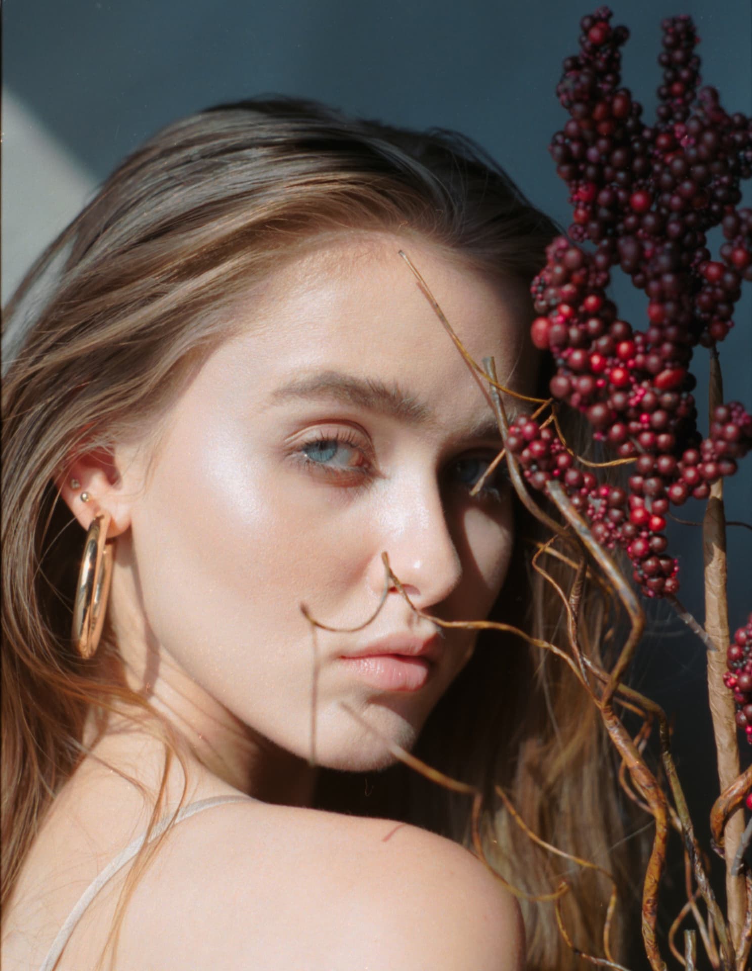 Close beauty portrait in hard sunlight beside deep red berries