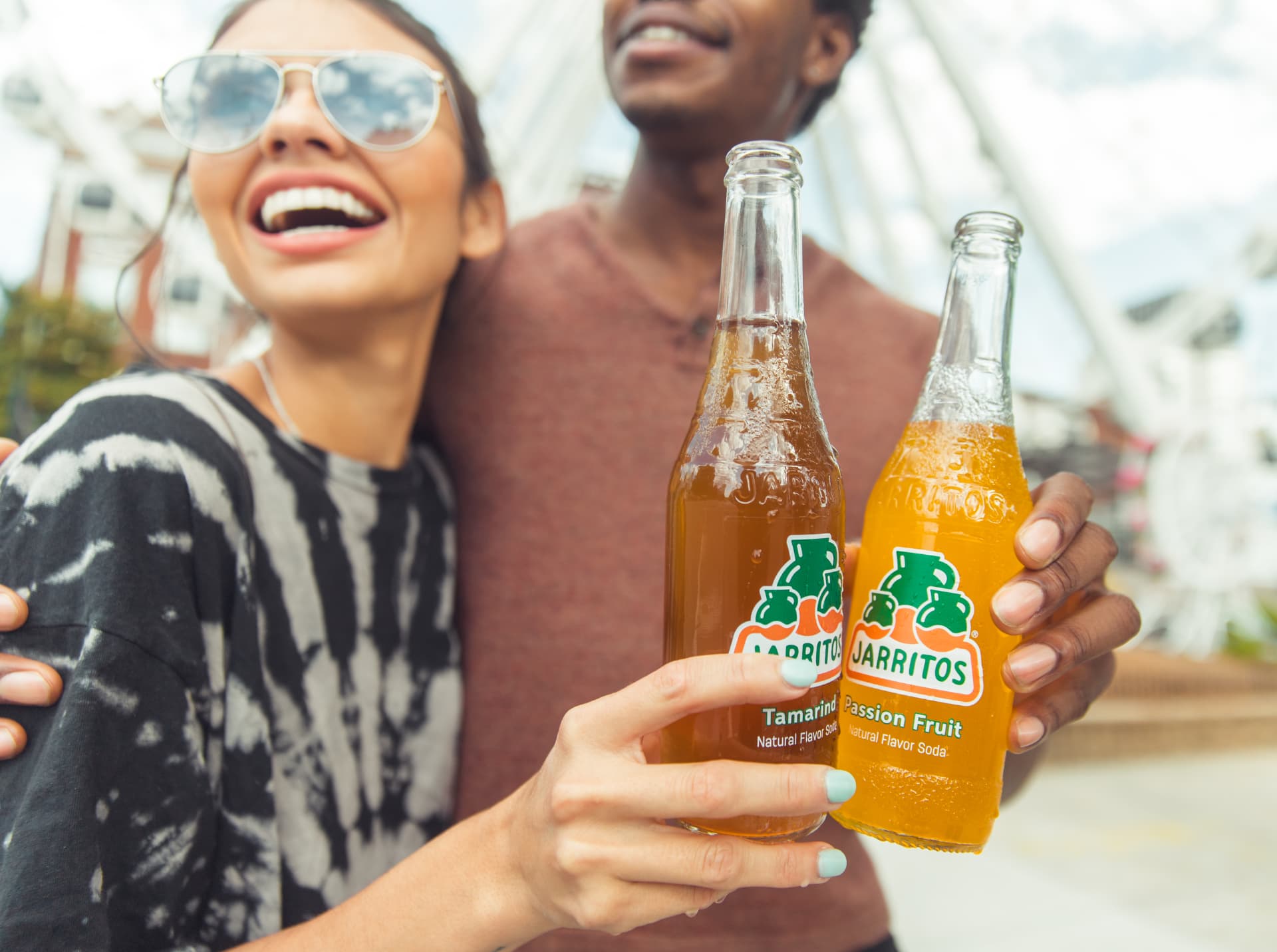 Close frame of two hands holding tamarind and passion fruit Jarritos bottles