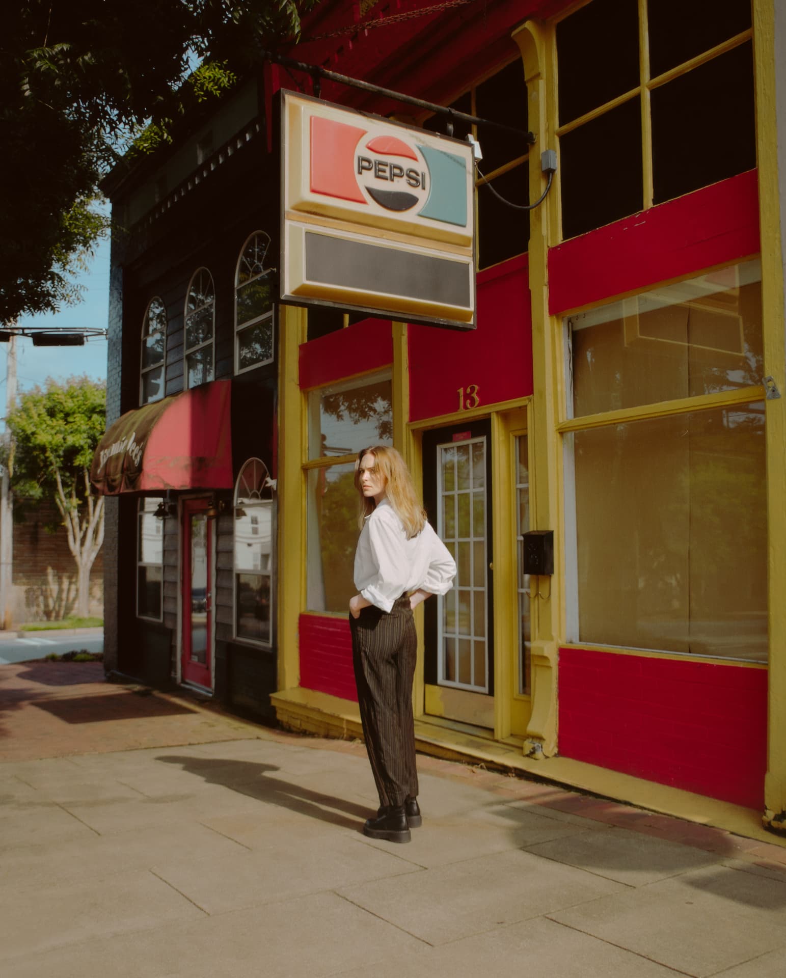 Portrait standing on a sidewalk beneath a vintage Pepsi sign