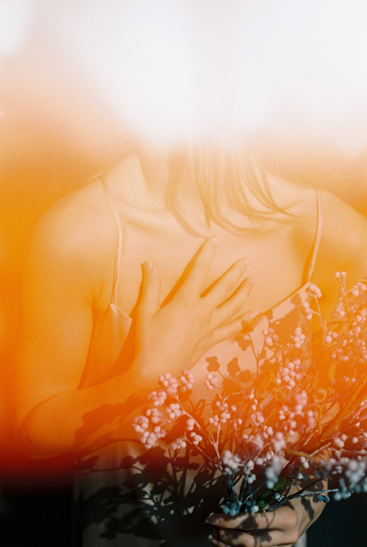 Film portrait with orange light leak holding dried flowers