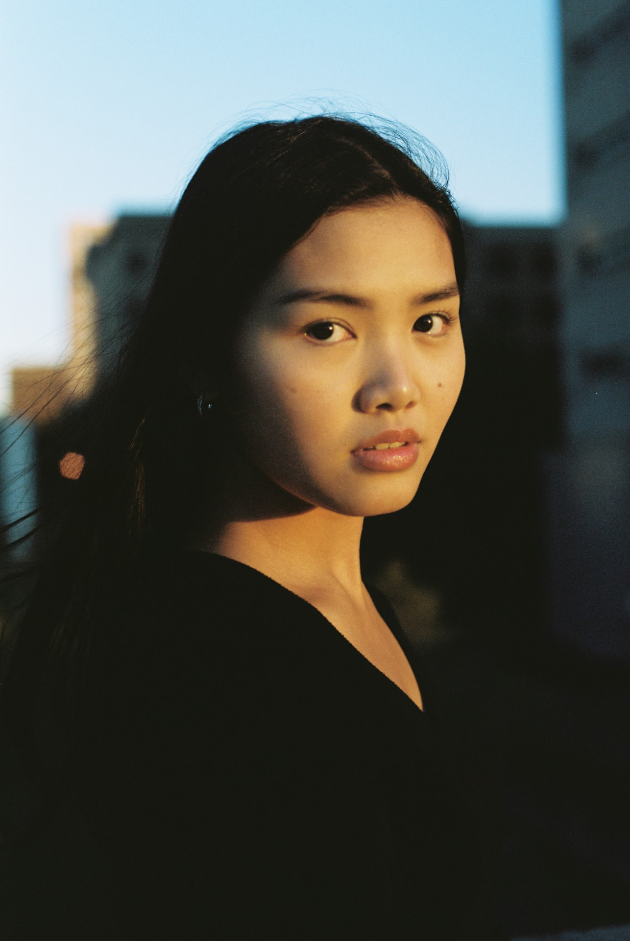 Film portrait in warm late light with city buildings behind