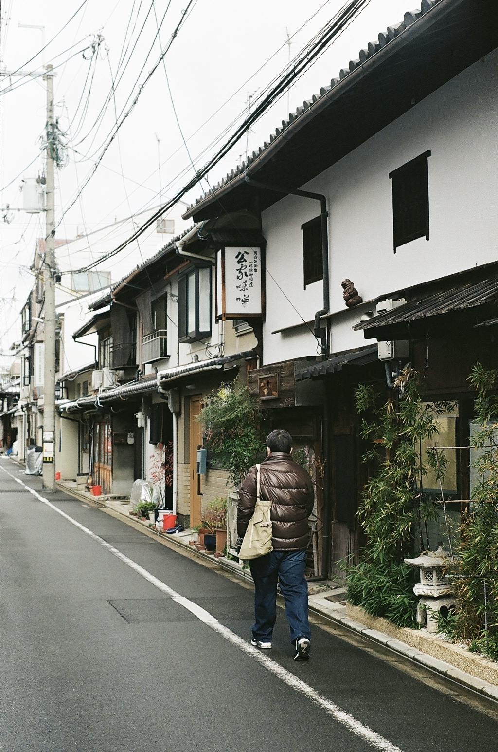 A man walking down a narrow street of traditional wooden houses