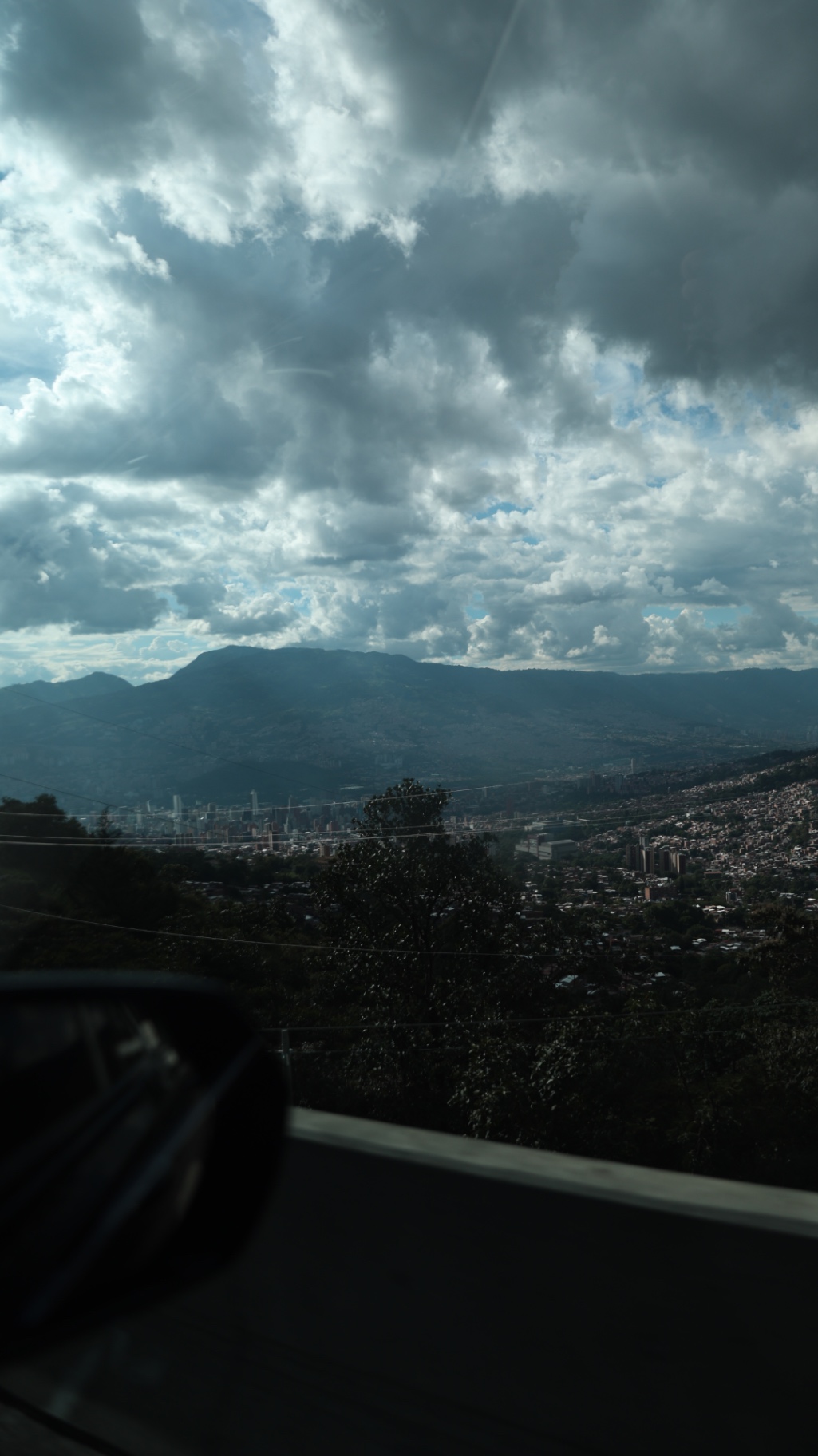 Mountains and city seen through a car window under heavy cloud