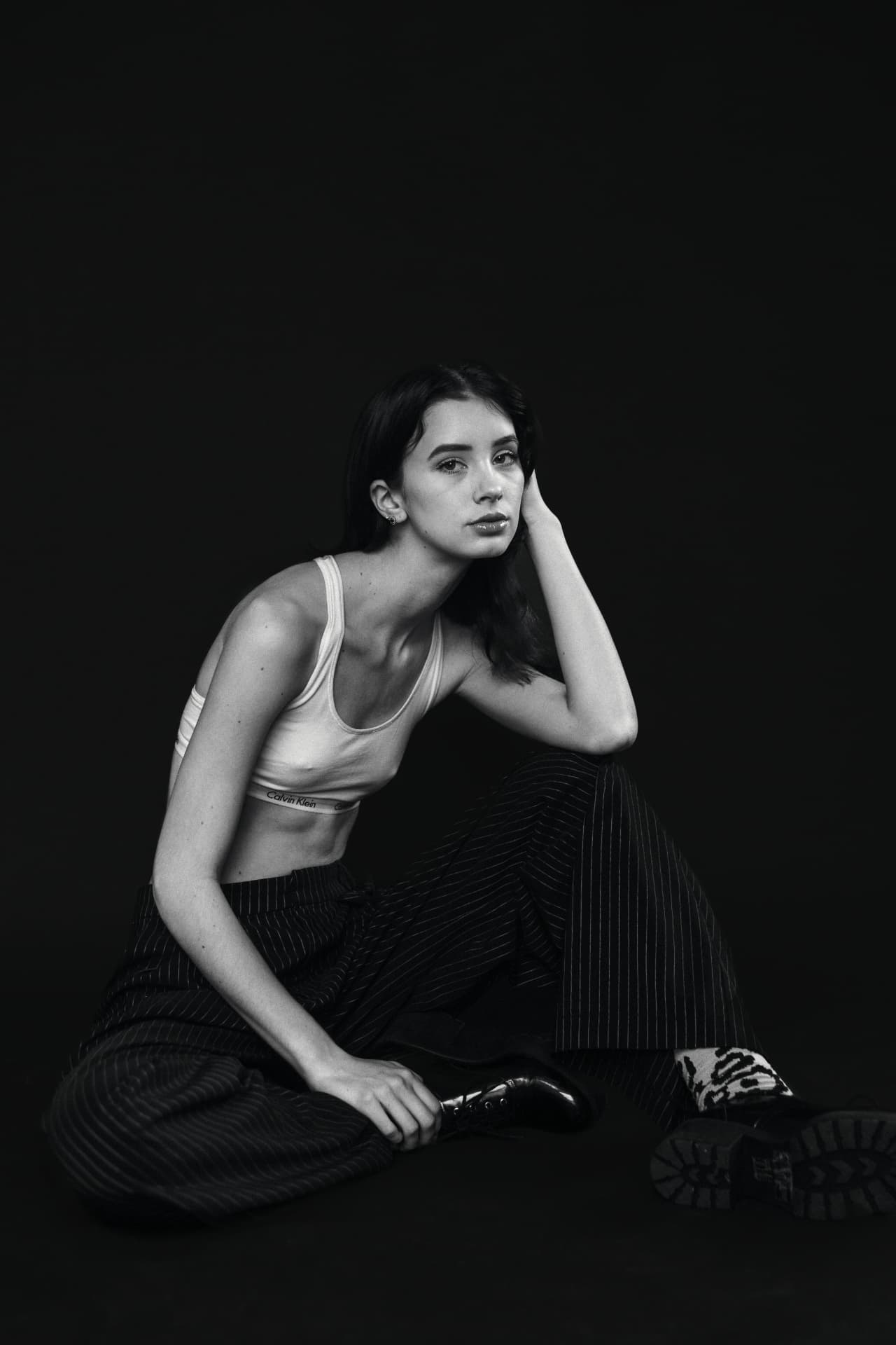 Black and white seated studio portrait against a dark backdrop
