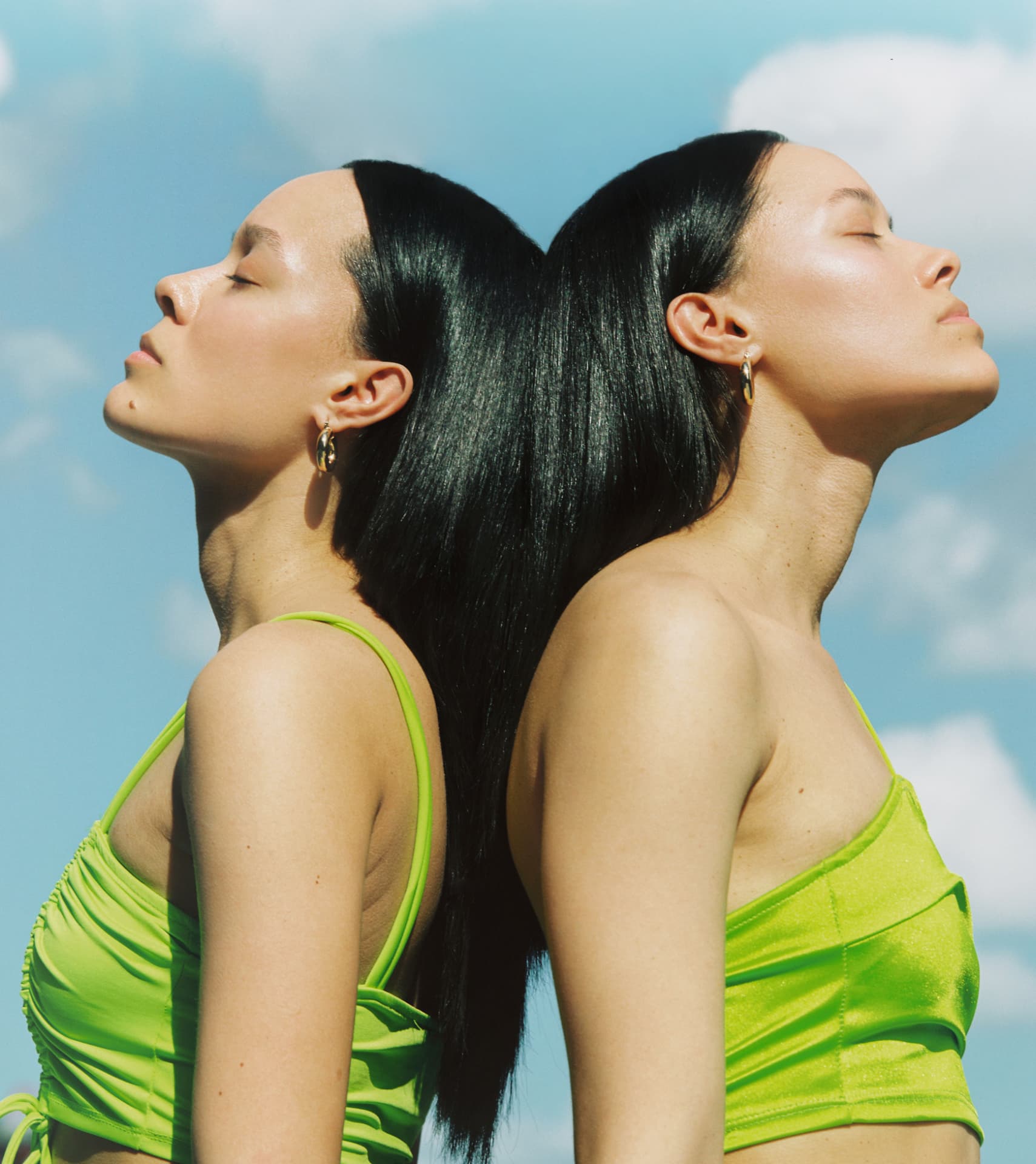 Two figures back to back in lime tops against a blue sky